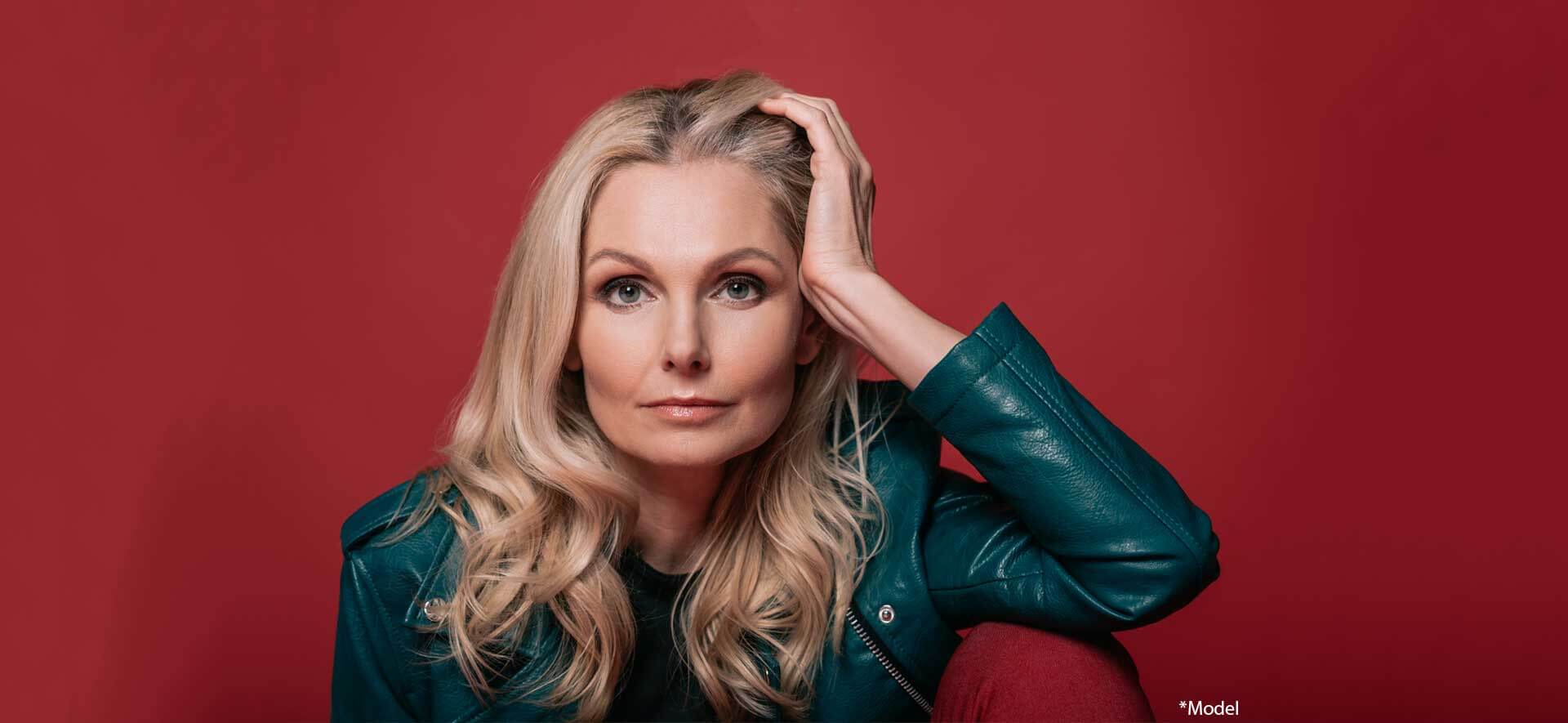 Close-up portrait of mature woman looking at camera isolated on red